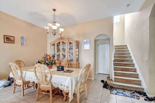 dining space with baseboards, arched walkways, a chandelier, stairs, and light tile patterned flooring