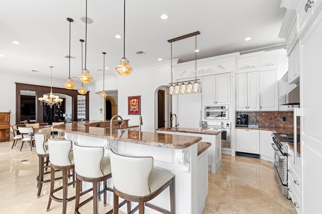 kitchen with a large island, white cabinets, stainless steel range, and hanging light fixtures