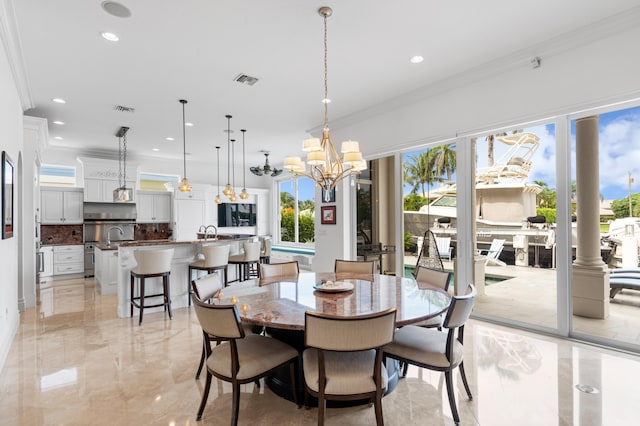 dining space featuring crown molding, a chandelier, and decorative columns