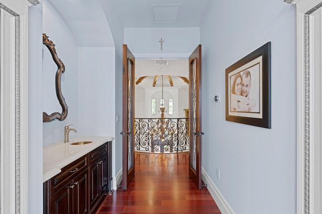 hallway featuring sink, dark hardwood / wood-style flooring, and an inviting chandelier