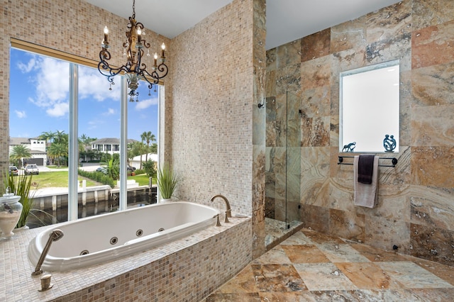 bathroom with a notable chandelier, independent shower and bath, and tile walls