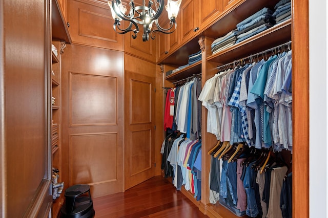 walk in closet with dark hardwood / wood-style flooring and an inviting chandelier