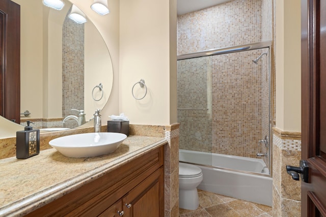 full bathroom with vanity, enclosed tub / shower combo, toilet, and tile patterned flooring