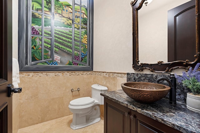 bathroom with toilet, vanity, tile walls, and tile patterned flooring