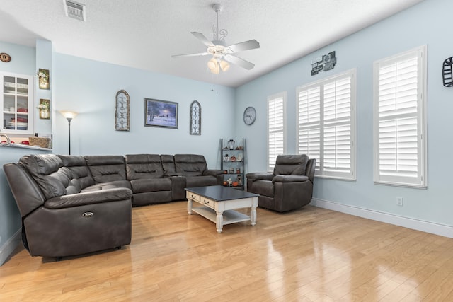 living room featuring ceiling fan, a textured ceiling, and light wood-type flooring