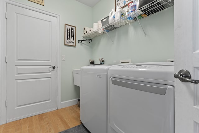 clothes washing area with washing machine and clothes dryer and hardwood / wood-style flooring