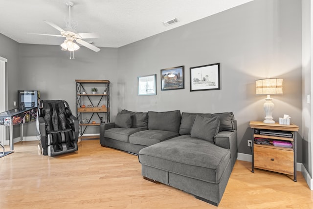 living room featuring ceiling fan, a textured ceiling, and light wood-type flooring