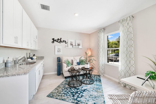 kitchen featuring white cabinetry, light stone countertops, light hardwood / wood-style flooring, and sink