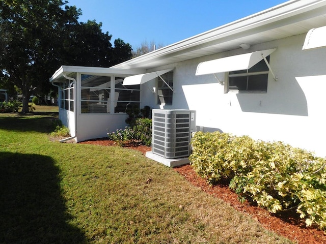 exterior space featuring central AC unit, a sunroom, and a lawn