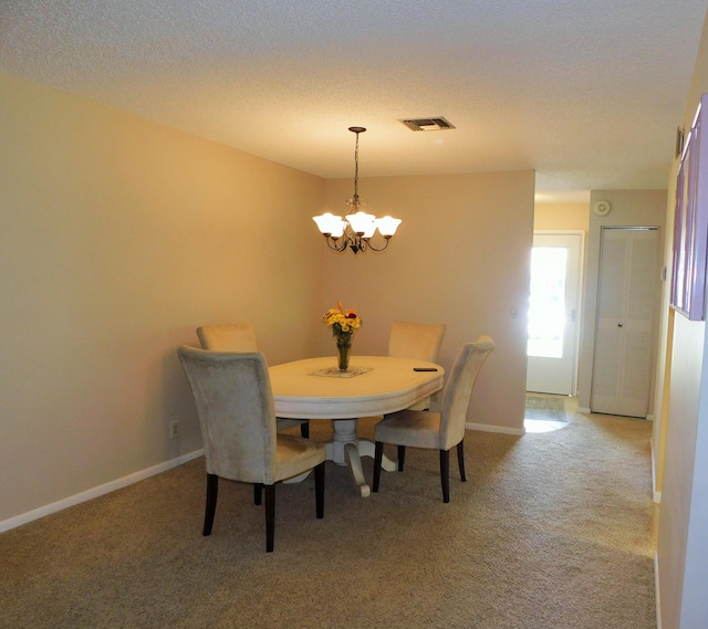 dining area with carpet floors, a chandelier, and a textured ceiling