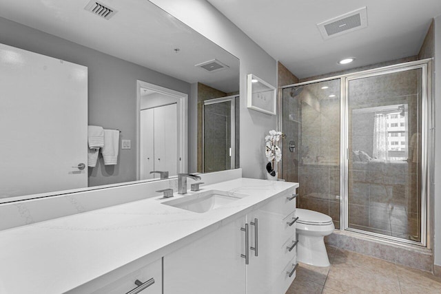 bathroom with vanity, a shower with shower door, toilet, and tile patterned floors