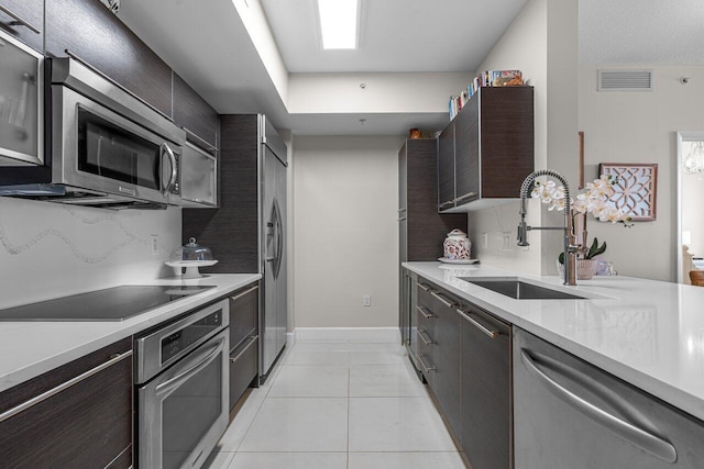 kitchen with decorative backsplash, stainless steel appliances, light tile patterned floors, and sink