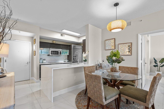 dining space with a textured ceiling, light tile patterned floors, and sink