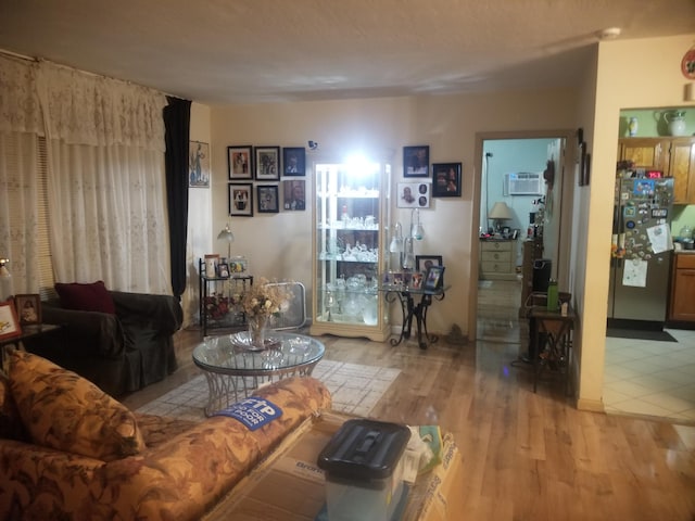 living room with a wall mounted AC and light wood-type flooring