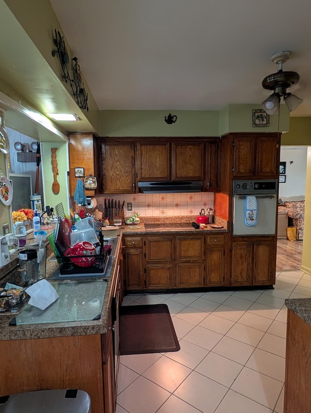 kitchen featuring backsplash, white oven, and light tile patterned floors