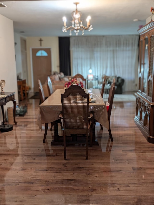 dining area featuring hardwood / wood-style flooring and an inviting chandelier