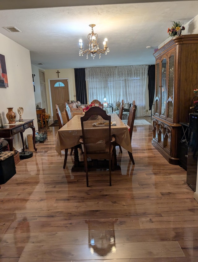 dining area featuring wood-type flooring and an inviting chandelier