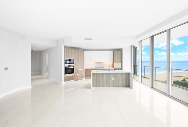 3100 N Ocean Dr Unit H-1508, Singer Island, FL 33404 - kitchen with modern cabinets, light countertops, a water view, baseboards, and an island with sink