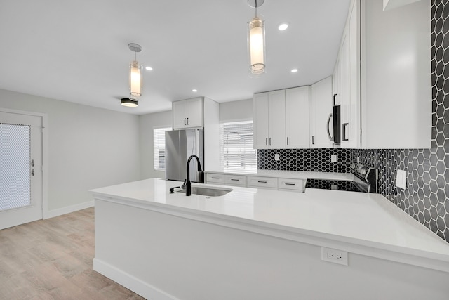 kitchen featuring white cabinets, appliances with stainless steel finishes, hanging light fixtures, and sink