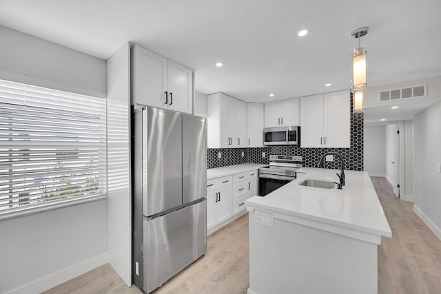 kitchen with pendant lighting, light hardwood / wood-style floors, sink, white cabinetry, and stainless steel appliances