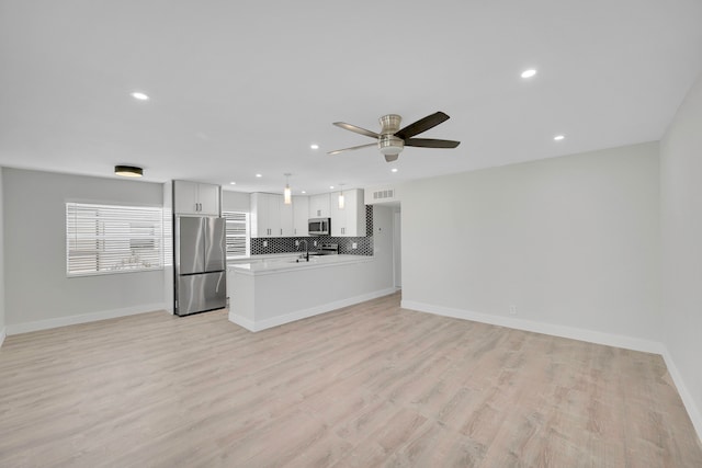 unfurnished living room featuring light hardwood / wood-style floors, sink, and ceiling fan