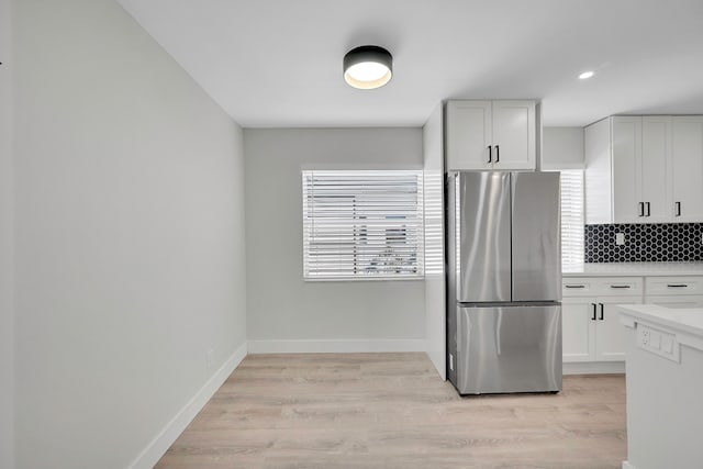 kitchen featuring light wood-type flooring, white cabinetry, a healthy amount of sunlight, and stainless steel fridge