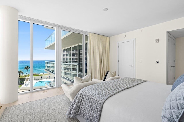 bedroom with a water view, hardwood / wood-style flooring, multiple windows, and access to exterior