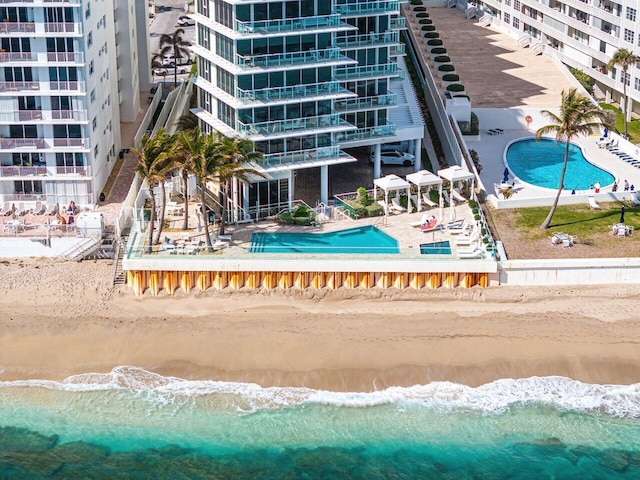 view of swimming pool with a patio, a water view, and a beach view