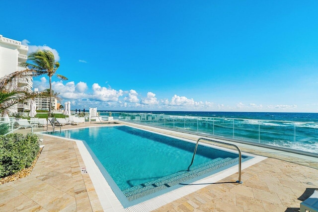 view of swimming pool featuring a patio and a water view