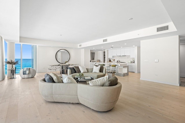 living room featuring a water view, expansive windows, and light wood-type flooring