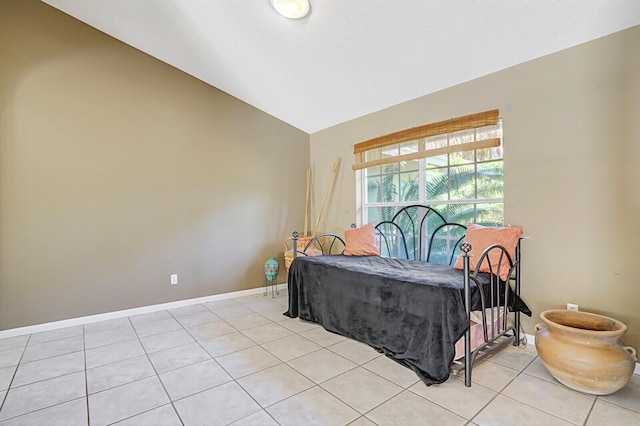 bedroom featuring light tile patterned floors, baseboards, and vaulted ceiling