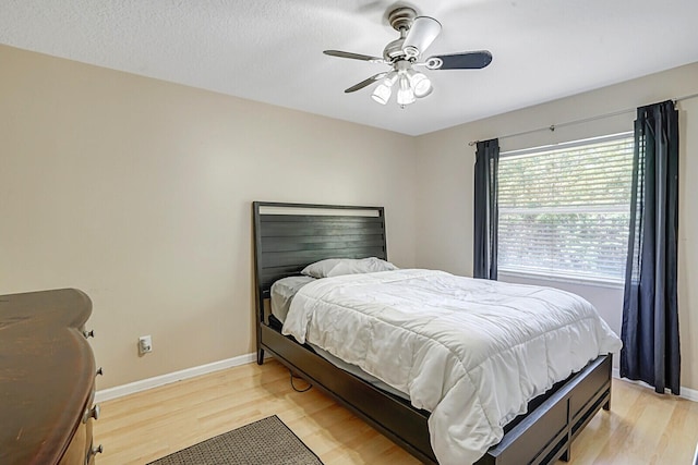 bedroom with light wood-style floors, baseboards, and ceiling fan