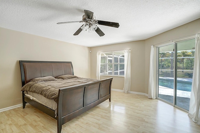 bedroom featuring access to exterior, baseboards, light wood-type flooring, and a textured ceiling