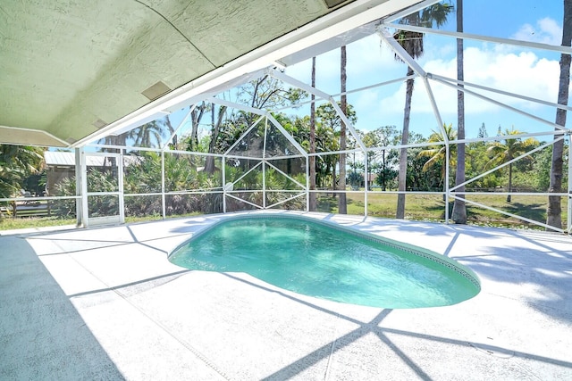 outdoor pool with glass enclosure and a patio area