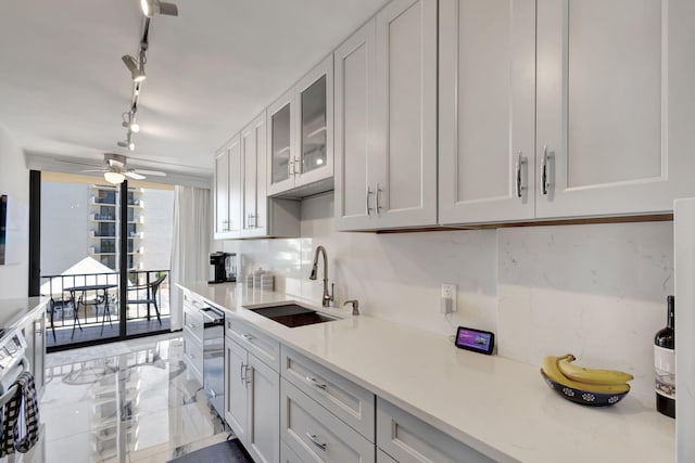 kitchen featuring rail lighting, sink, stainless steel appliances, light stone countertops, and white cabinetry