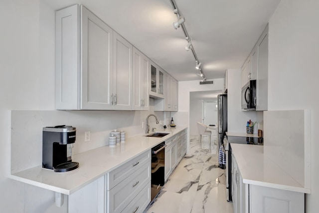 kitchen with white cabinets, sink, track lighting, stainless steel appliances, and a breakfast bar area