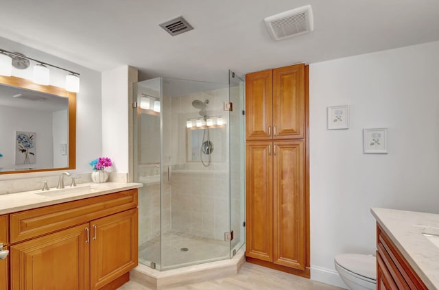 bathroom featuring hardwood / wood-style floors, toilet, vanity, and a shower with shower door