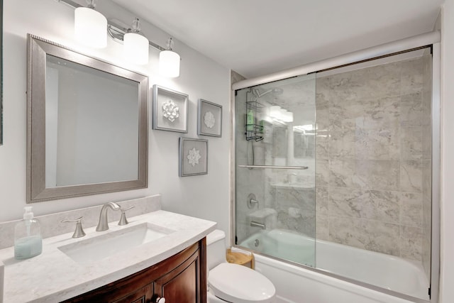 full bathroom with combined bath / shower with glass door, toilet, and vanity