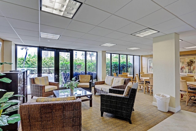 living room with french doors, a drop ceiling, floor to ceiling windows, and a wealth of natural light