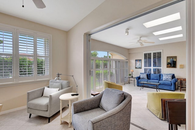 tiled living room featuring ceiling fan, plenty of natural light, and a skylight