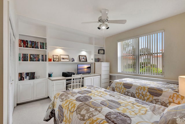 carpeted bedroom featuring ceiling fan and built in desk