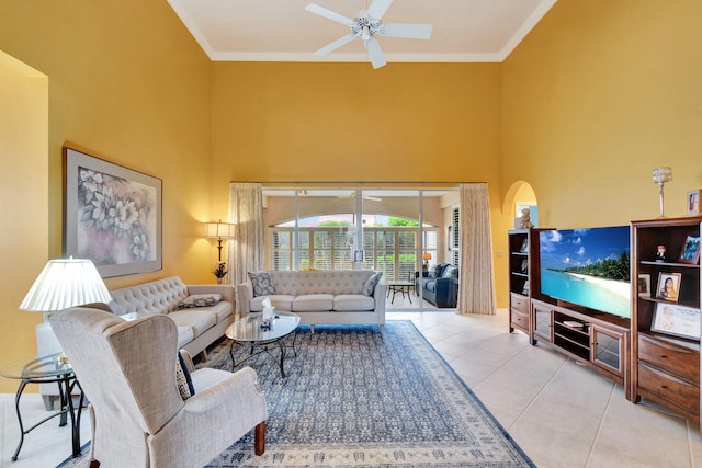 living room featuring a towering ceiling, ornamental molding, light tile patterned floors, and ceiling fan