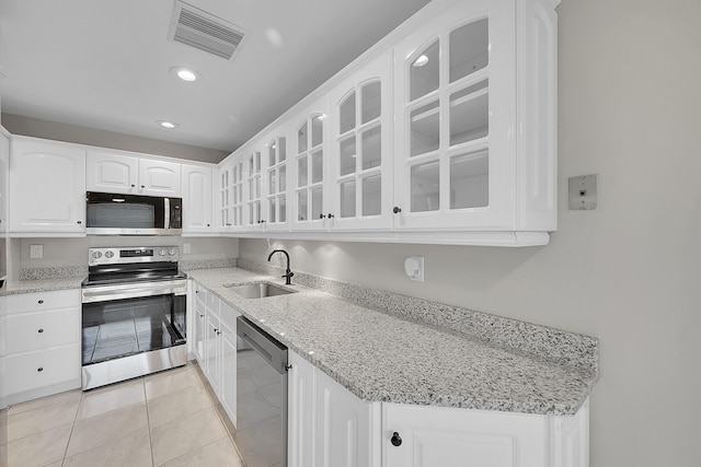 kitchen with white cabinets, light tile patterned flooring, sink, appliances with stainless steel finishes, and light stone countertops