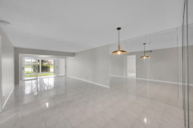 unfurnished room with a textured ceiling and light tile patterned floors