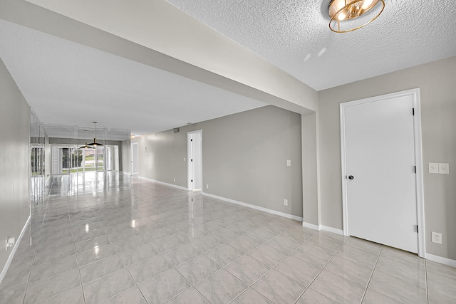 tiled empty room featuring a textured ceiling