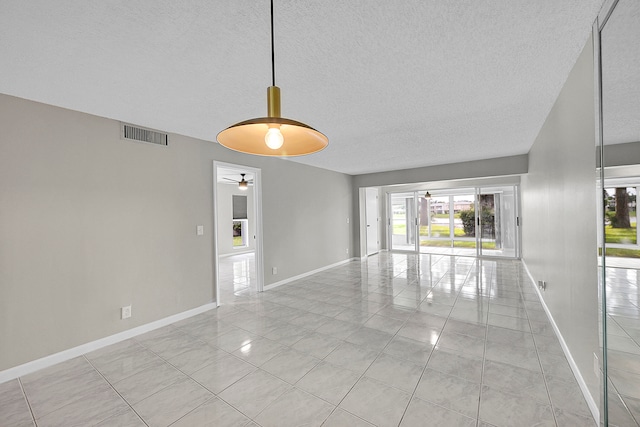 tiled spare room with a textured ceiling and ceiling fan