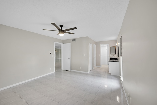 tiled spare room with ceiling fan and a textured ceiling