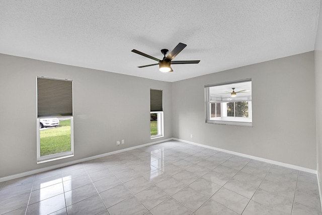 spare room featuring a textured ceiling, light tile patterned floors, ceiling fan, and a wealth of natural light