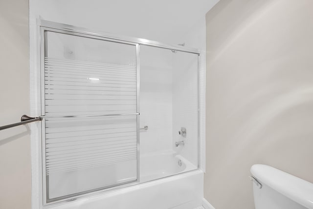 bathroom with combined bath / shower with glass door and toilet