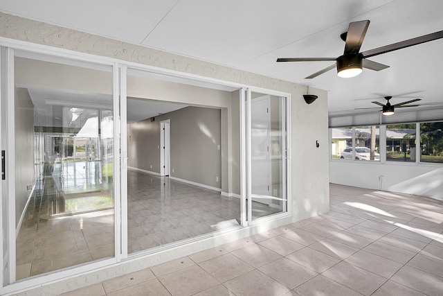 tiled empty room with ceiling fan and plenty of natural light